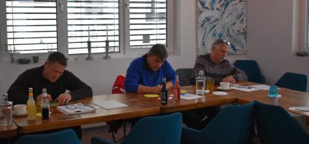 Three people sitting at tables and writing