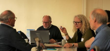 five participants of a workshop during a discussion, one looking at his notebook