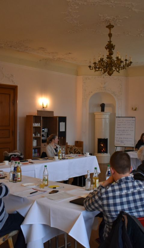 people in a baroque room listening to a presentation