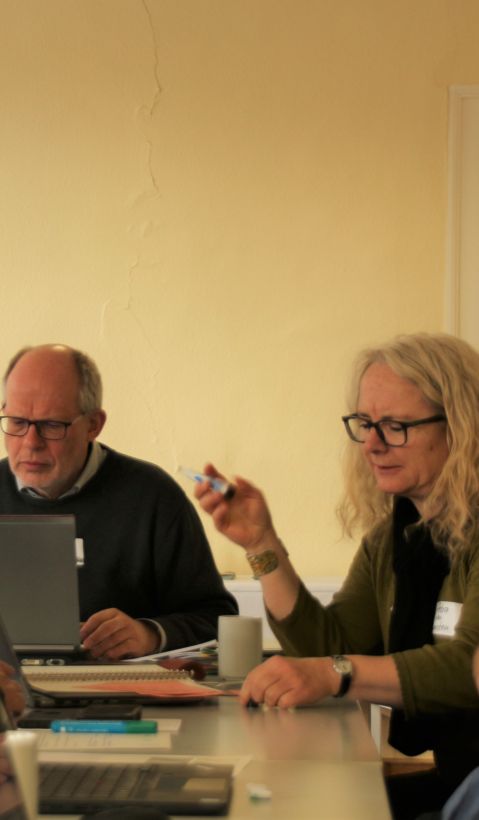 five participants of a workshop during a discussion, one looking at his notebook